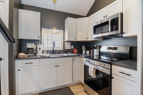 a kitchen with white cabinets and a stove top oven at Pelican Cliff Cottage - Tiny Home at Hampton Beach in Hampton