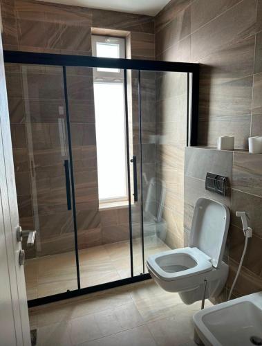 a bathroom with a toilet and a glass shower at Diva Chalet in Sowayma
