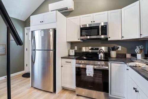 a kitchen with white cabinets and a stainless steel refrigerator at Sandy Toes Cottage - Tiny Home at Hampton Beach in Hampton