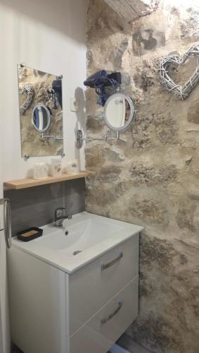 a bathroom with a sink and a mirror on a stone wall at Mas de chalvagne in Val-de-Chalvagne