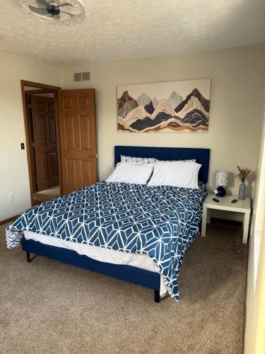 ein Schlafzimmer mit einem Bett mit einer blau-weißen Bettdecke in der Unterkunft The Wright Stay in Dayton