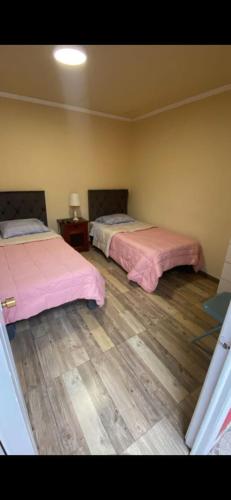 two beds in a room with wooden floors at Hotel Centro in Copiapó