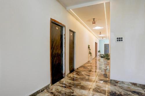 a hallway with white walls and a wooden door at Hotel O MK2 Hotel and Restaurant in Indore