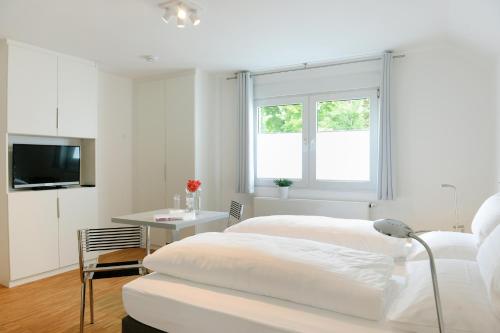 - une chambre blanche avec un lit et une table dans l'établissement Bed & Breakfast Meerbusch, à Meerbusch