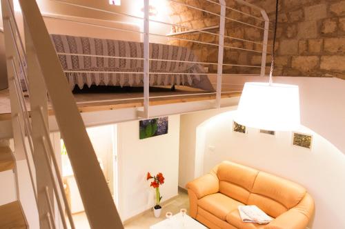 a loft bed in a tiny room with a couch at Murgia Dreams in Altamura