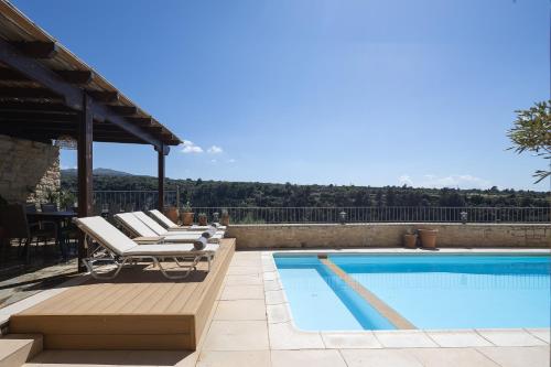 a swimming pool with lounge chairs next to a swimming pool at Ilys Home, a Country-chic Retreat with Pool & BBQ, By ThinkVilla in Margarítai