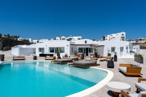 a pool in front of a villa with white buildings at Oikos Santorini Living Concept in Fira