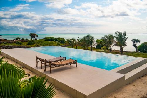 a swimming pool with a bench next to the ocean at Villa Kweli - Private Ocean Front Villa in Tongoni
