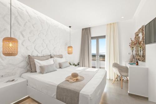 a white bedroom with a bed with a hat on it at Naxian Pearl in Mikri Vigla