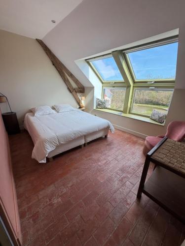 a bedroom with a bed and two large windows at Appartement spacieux au domaine in Coust