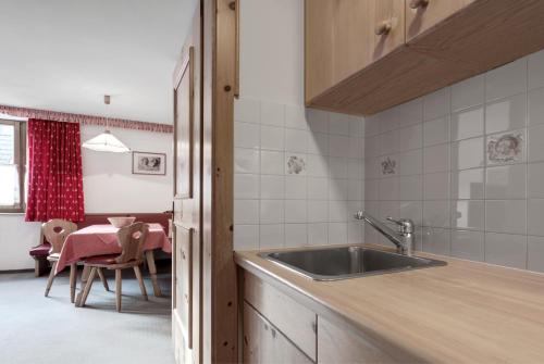 a kitchen with a sink and a dining table at Residence Dolomieu in San Cassiano