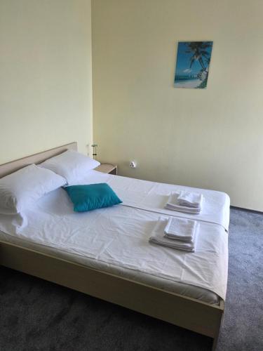 a bed with a blue pillow and towels on it at The Yellow House in Ahtopol
