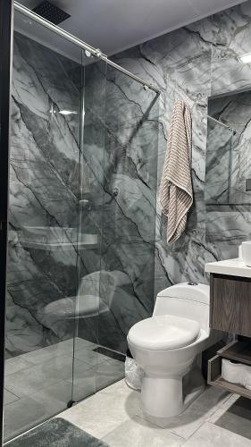 a bathroom with a toilet and a glass shower at Hospedaje choachi Housetraillyones in Choachí