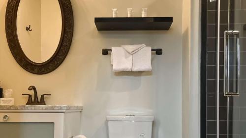 a bathroom with a mirror and a toilet and a sink at Midnight Sun, a Coast Hotel in Dawson City