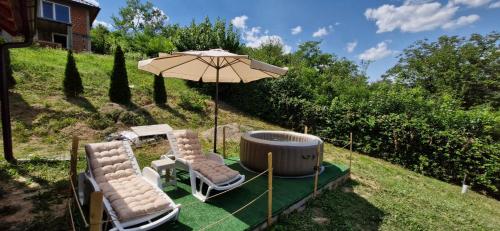 a hot tub with two chairs and an umbrella at Vikendica Monte in Ledinci