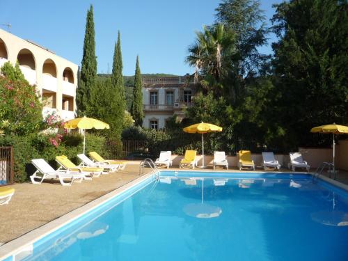 - une piscine avec des chaises et des parasols à côté d'un bâtiment dans l'établissement Le Roussillon, à Amélie-les-Bains-Palalda