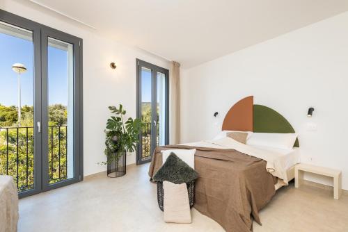 a white bedroom with a bed and large windows at Via Tirso Rooms & Studio in Tortolì