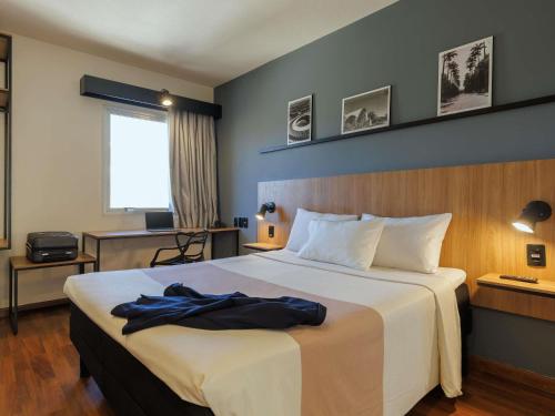 a hotel room with a bed with a robe on it at ibis Belo Horizonte Liberdade in Belo Horizonte