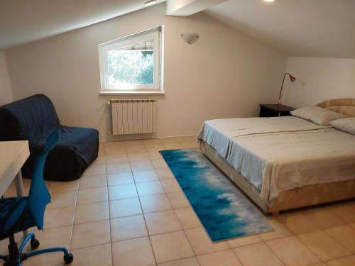 a bedroom with a bed and a chair and a window at Apartma Viva in Ankaran