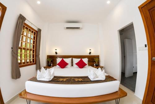 a bedroom with a white bed with red pillows at Poolside Villa in Phnom Penh