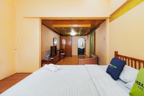 a bedroom with a white bed and a living room at Urbanview My Grand Hotel Bogor in Brujul