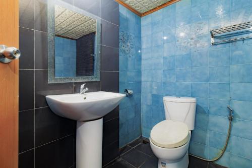 a blue tiled bathroom with a toilet and a sink at Urbanview My Grand Hotel Bogor in Brujul