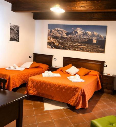 a hotel room with two beds with orange sheets at Tenuta VERBICARO in Morano Calabro