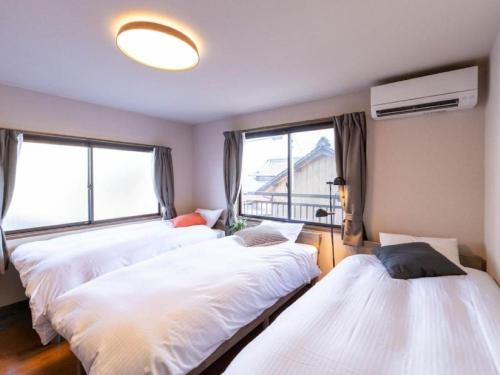 a bedroom with three beds and a window at ゲストハウス あぽわん 貸切宿無料駐車場 in Mitoyo