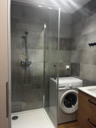 a shower stall in a bathroom with a washing machine at Apartament Kopernikus in Grodzisk Mazowiecki