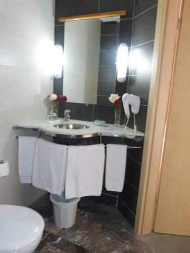 a bathroom with a sink and a toilet and towels at Hotel Arena Fes in Fès