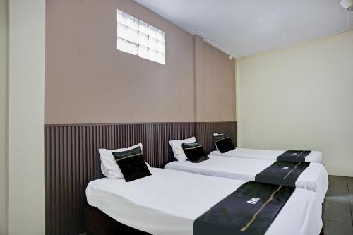 two beds in a room with white sheets and black pillows at Hotel O Kuta Alam Near Masjid Oman Al-Makmur Formerly Daka Hotel in Lheue