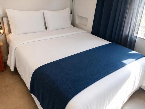 a bedroom with a large white bed with a blue blanket at Studiohaus Alvorada in São Paulo