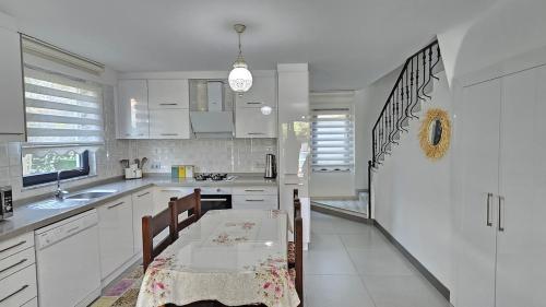 a kitchen with white cabinets and a dining table at Villa Zümrüt in Ortaca