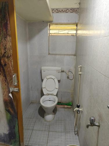 a small bathroom with a toilet in a stall at Sri Sai Lodge in Palni