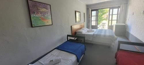 a small room with two beds and a window at Vila Hibisco Pousada Saquarema in Saquarema