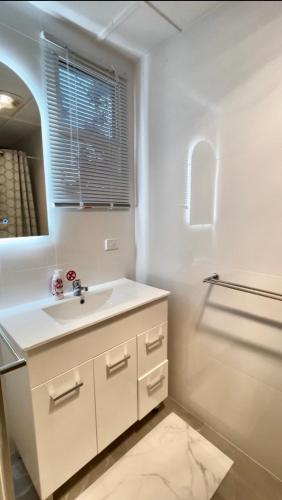 a white bathroom with a sink and a mirror at Overwater on the Murray in Murray Bridge