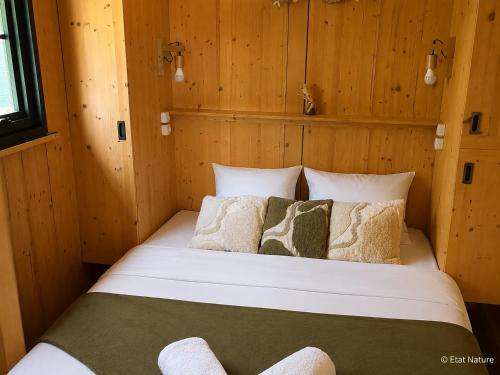 a bed in a room with wooden walls at Tiny house - Cabane sur pilotis - Etat Nature in Magnières