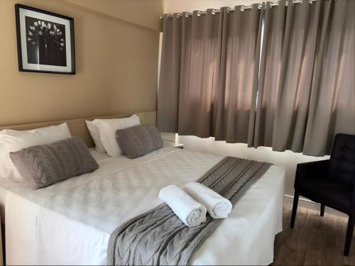 a bedroom with a large white bed with towels on it at Hotel Itajaí Tur - Itajaí Navegantes in Itajaí
