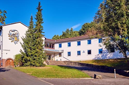 a white building with a tree in front of it at DJH Jugendherberge Hagen in Hagen