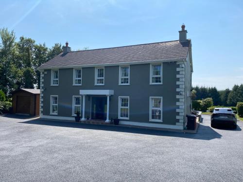 a large blue house with a car parked in front at Room One Stay in Corran Cross Roads