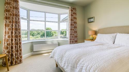 a bedroom with a bed and a large window at Glangors in Abersoch