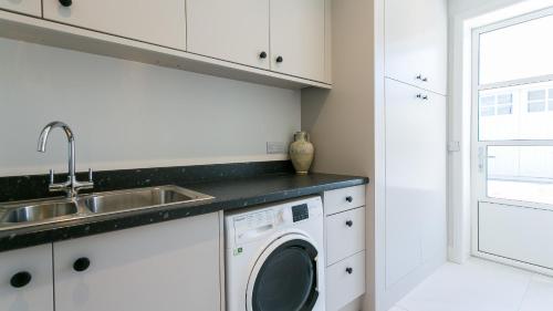 a kitchen with a sink and a washing machine at Glangors in Abersoch