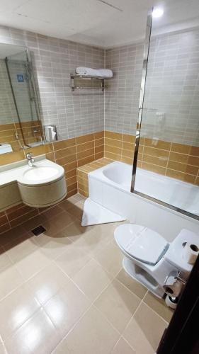 a bathroom with a toilet and a tub and a sink at فندق دولف in Al Khobar