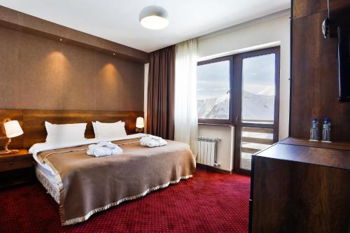 um quarto de hotel com uma cama e uma janela grande em Hotel Carpe Diem Gudauri em Gudauri