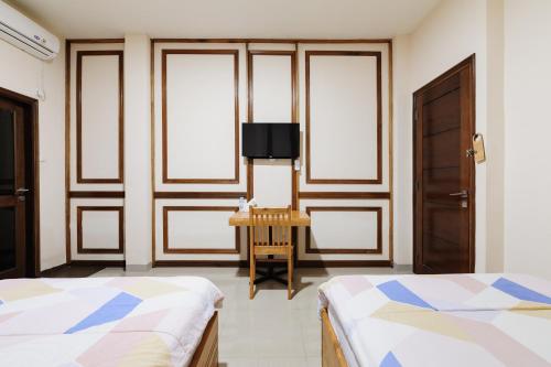 a room with two beds and a table and windows at Urbanview Remington Hotel Palembang By RedDoorz in Palembang