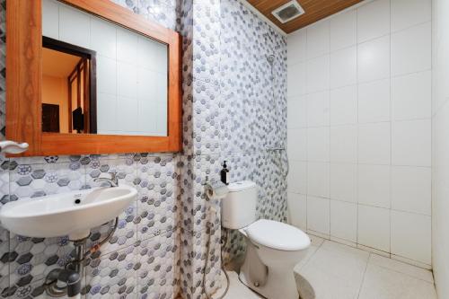 a bathroom with a sink and a toilet and a mirror at Urbanview Remington Hotel Palembang By RedDoorz in Palembang
