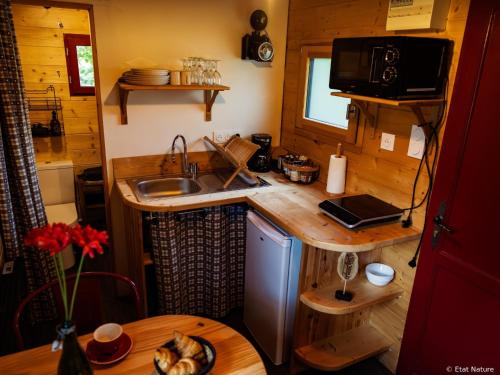 a kitchen in a tiny house with a sink and a table at Roulotte - Etat Nature in Magnières