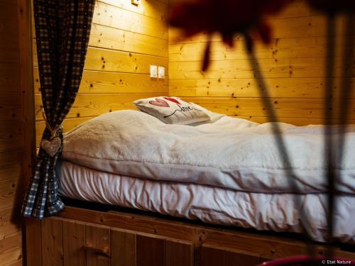 a bed in a room with a wooden wall at Roulotte - Etat Nature in Magnières
