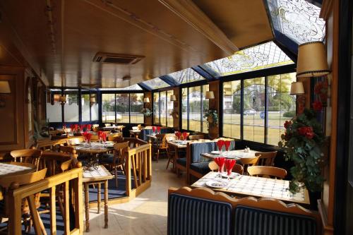 un restaurante con mesas, sillas y ventanas en Le Refuge du P'tit Fischer, en Argentan