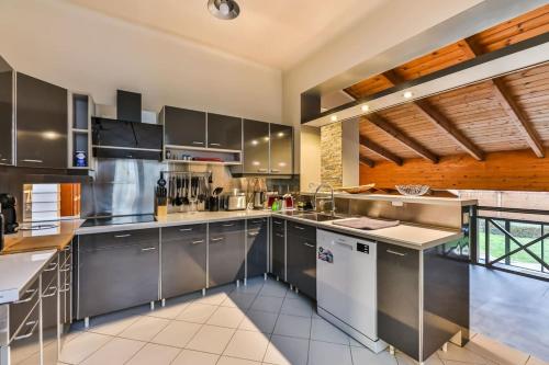 a large kitchen with stainless steel appliances and wooden ceilings at L'atypique - Piscine intérieure - Wifi in Challans